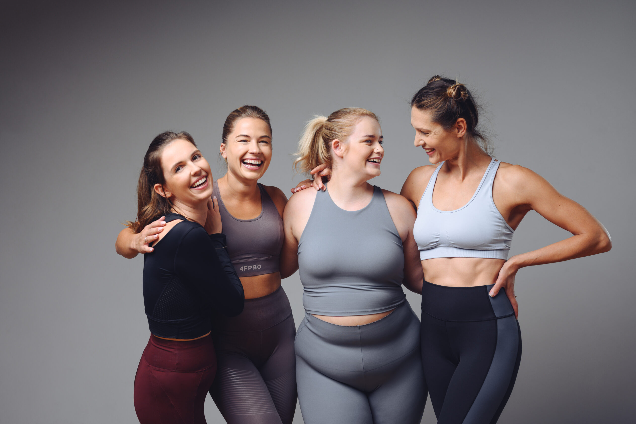 Grupa uśmiechniętych kobiet w strojach sportowych podczas wspólnych zajęć fitness