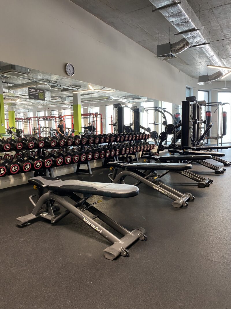 Strefa wolnych ciężarów z ławami prostymi – Well Fitness Katowice Wrocławska.