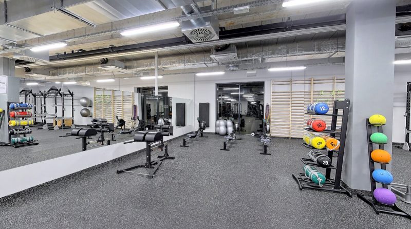 Sala do ćwiczeń wytrzymałościowych, z maszynami, obciążeniami i piłkami oraz lustrem i drabinkami.