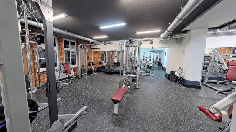 Sala do ćwiczeń ogólnorozwojowych. Na śródku stoi ławeczka oraz wyciągi.