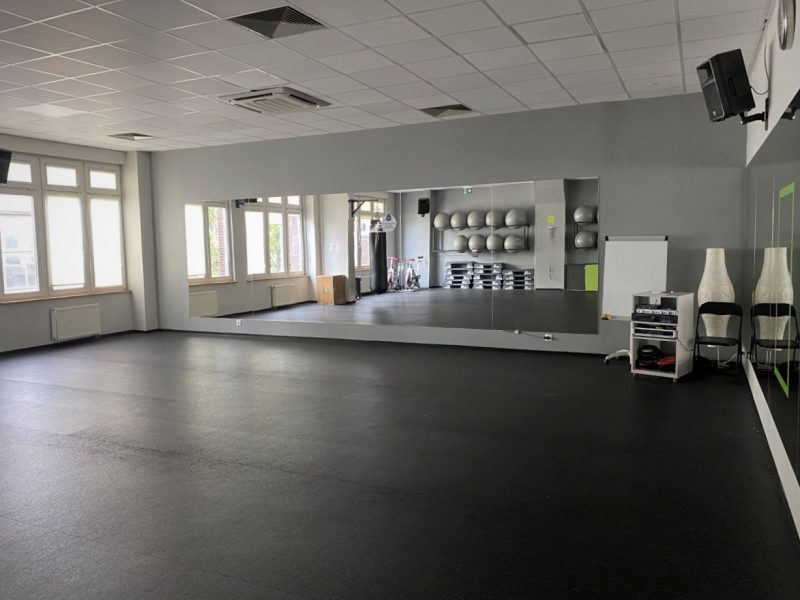 Sala fitness z lustrem i oknem po lewej stronie.