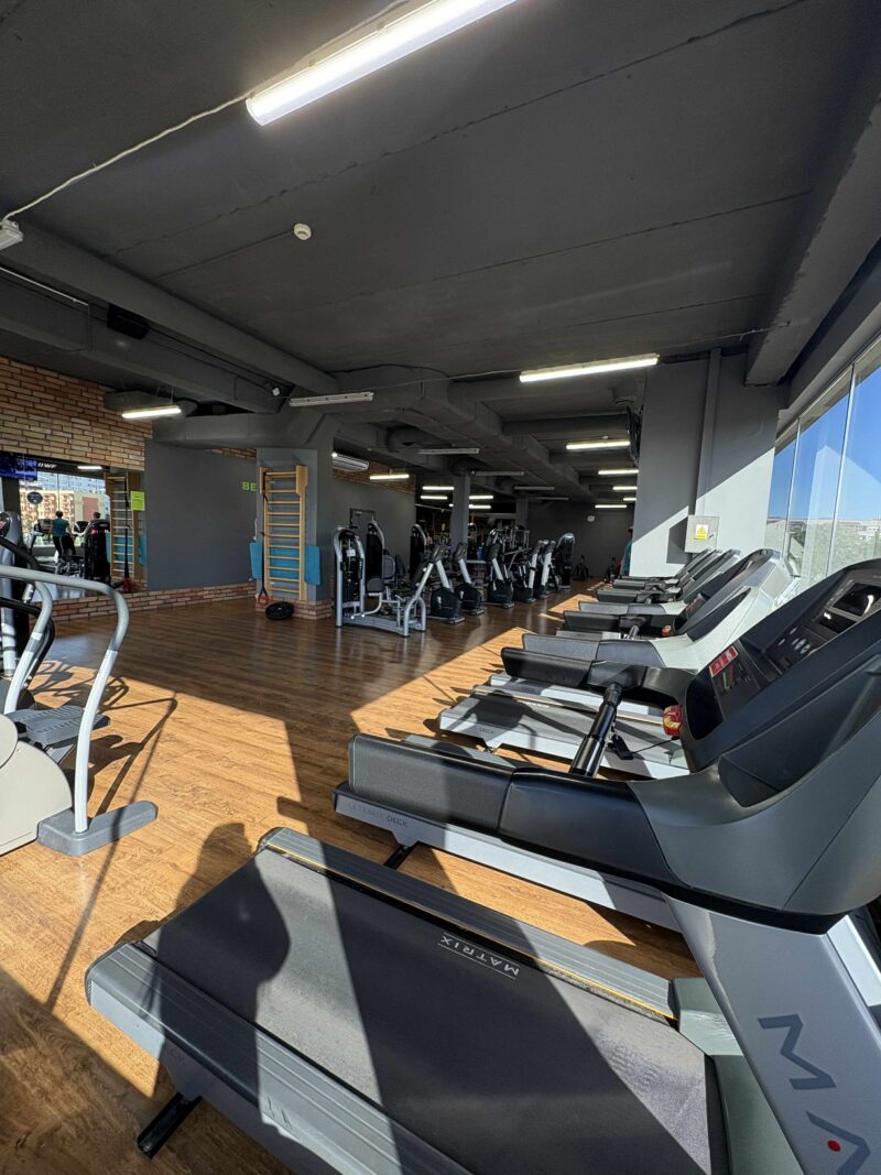 Bieżnie i rowerki stacjonarne w jasnej strefie cardio.