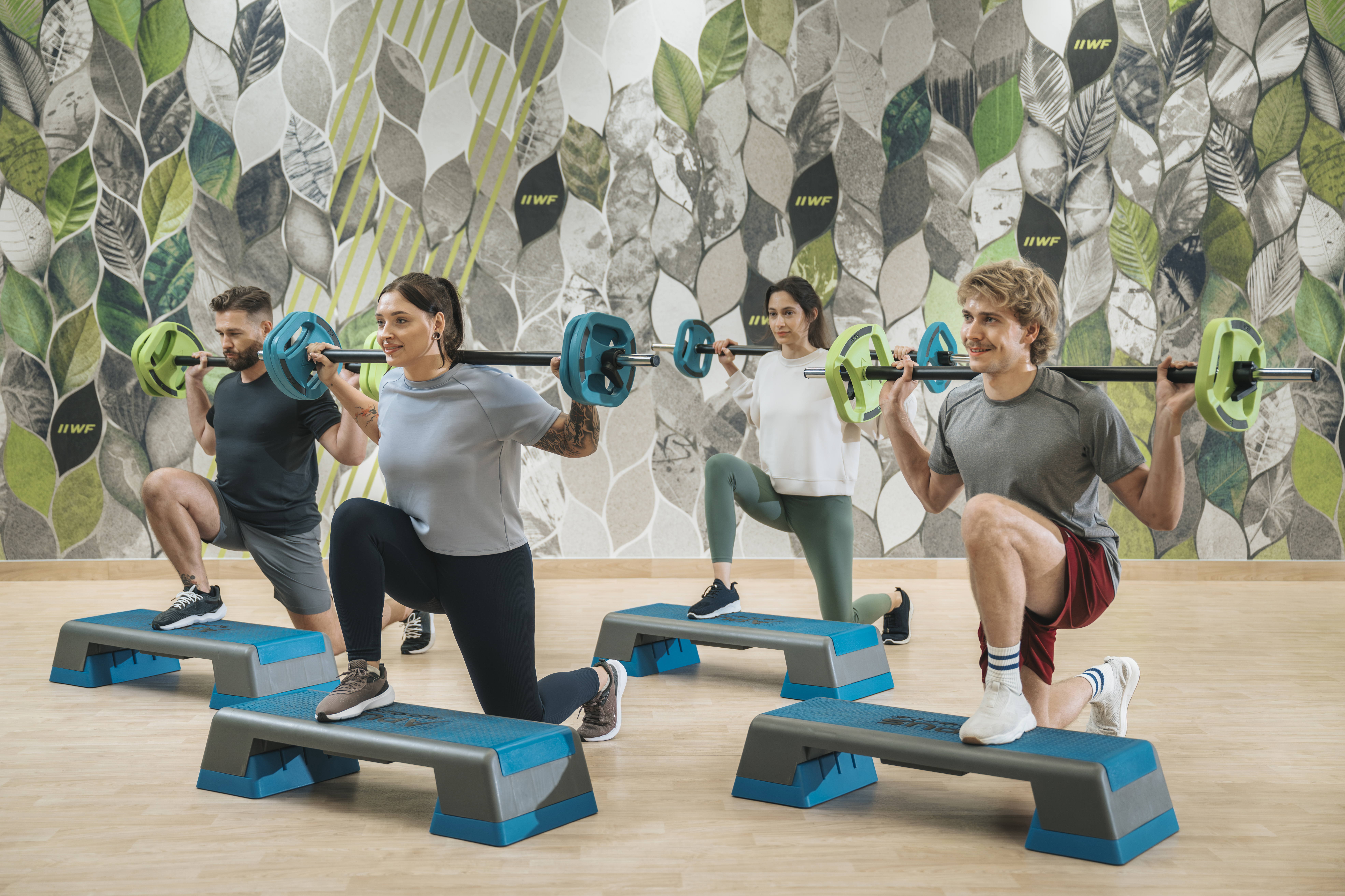 grupa ludzi, wykonująca ćwiczenia z obciążeniem podczas zajęć grupowych w Well Fitness