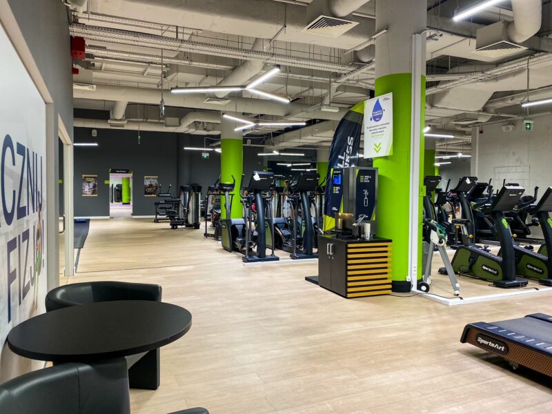 Korytarz przy otwartej strefie treningowej – Well Fitness Poznań Półwiejska