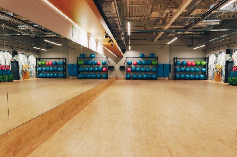 Przestronna sala fitness z wyposażeniem do zajęć grupowych – hantle, piłki i maty w Well Fitness Gdańsk Oliwa