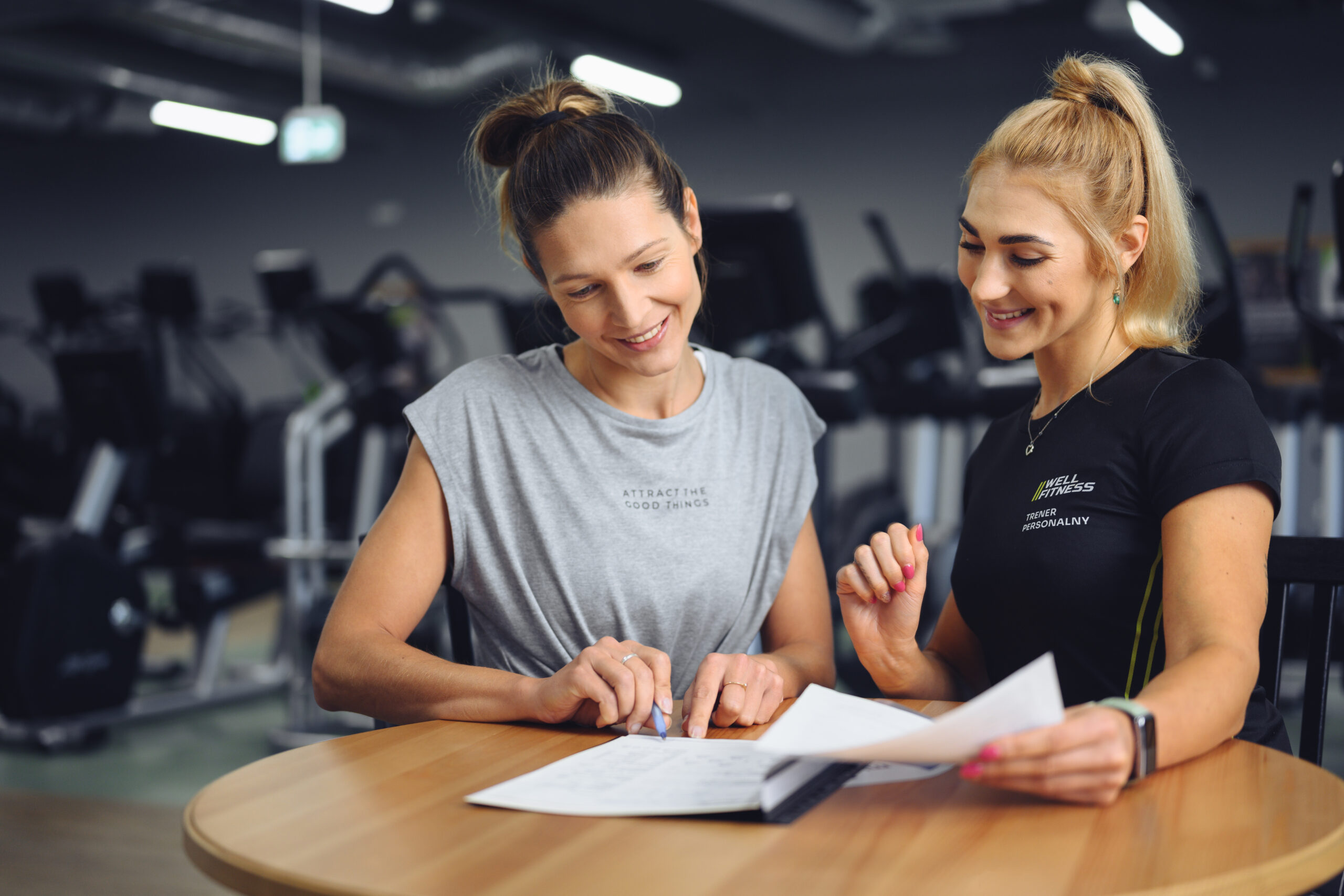 Trener personalny Well Fitness podczas konsultacji z klubowiczem na siłowni