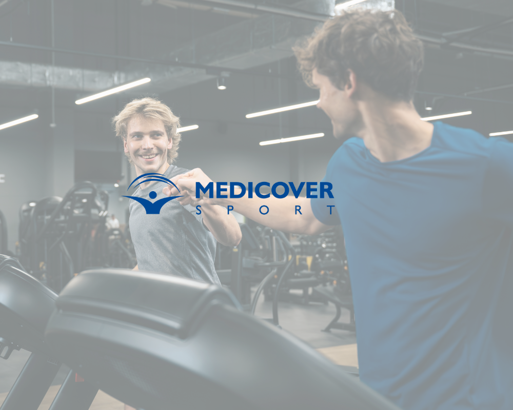 Dwóch mężczyzn biegnących na bieżniach w siłowni, oferta dostępna z kartą Medicover Sport.